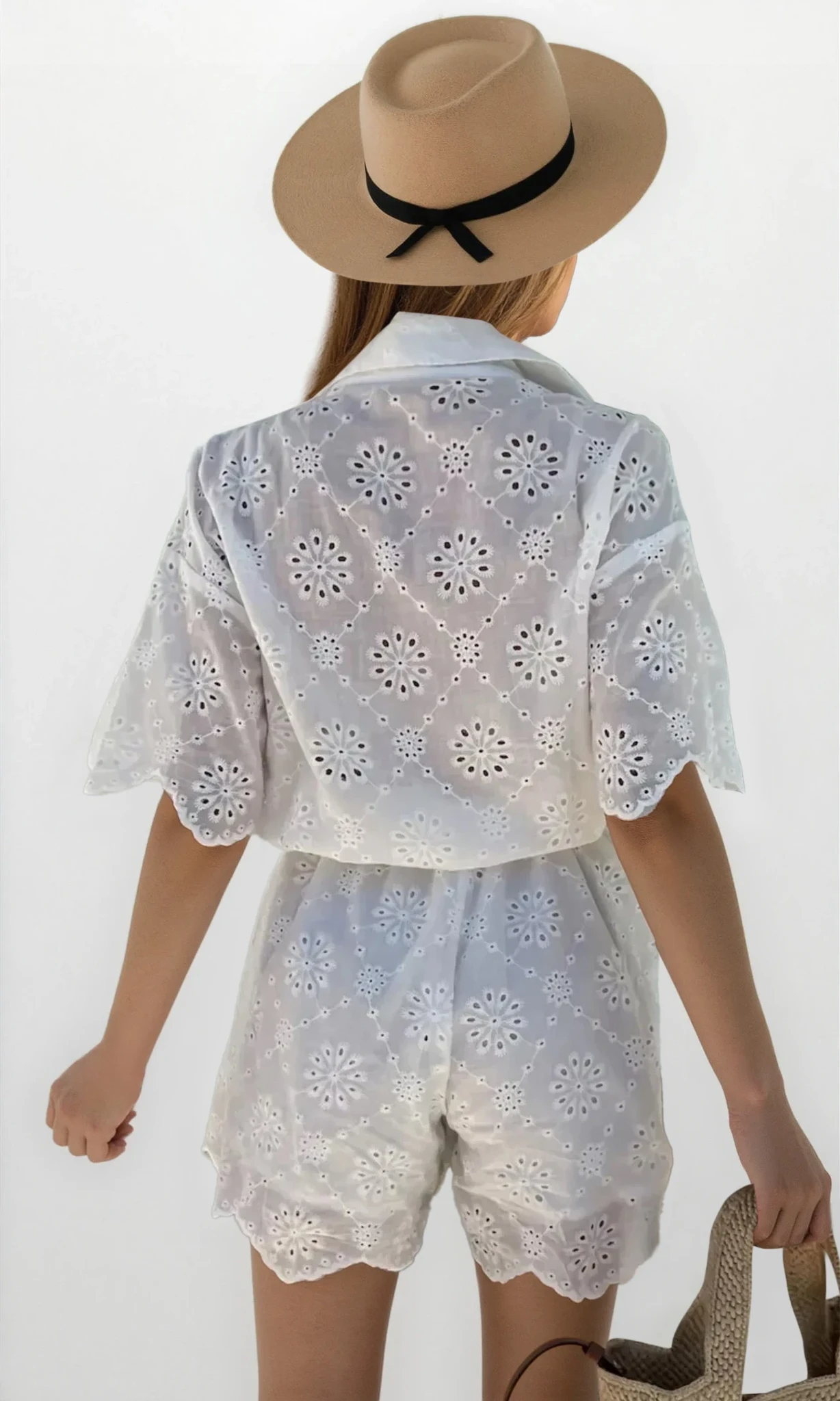 Elysia eyelet lace button-up romper by Trendsi, featuring a light fabric with lace details and a collar, displayed on a hanger.