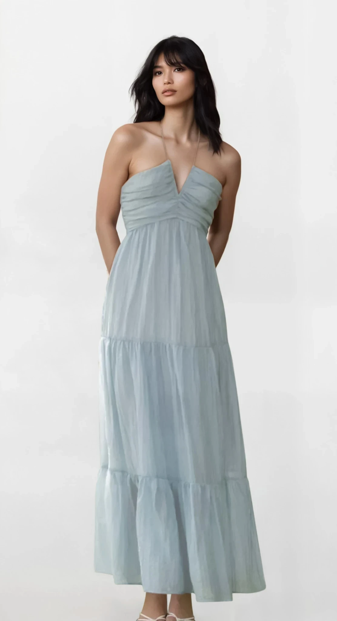 Light blue Solstice Halter Neck Tiered Cami Dress by Trendsi displayed on a hanger, showcasing its flowy, tiered design and halter neckline.